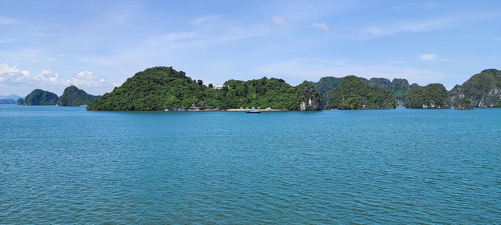 Limestone karst islands rise from turquoise waters under a clear sky in Ha Long Bay. Limestone karst islands rise from turquoise waters under a clear sky in Ha Long Bay.